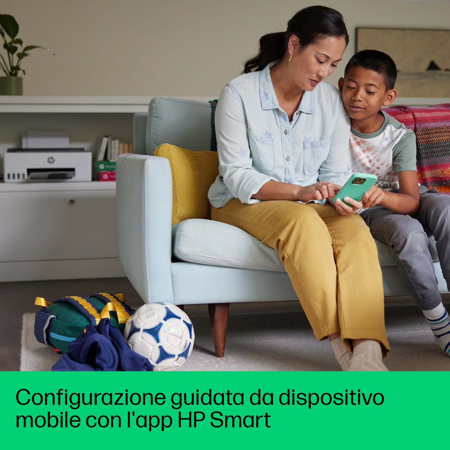 Una madre e un figlio che usano un telefono seduti su un divano.