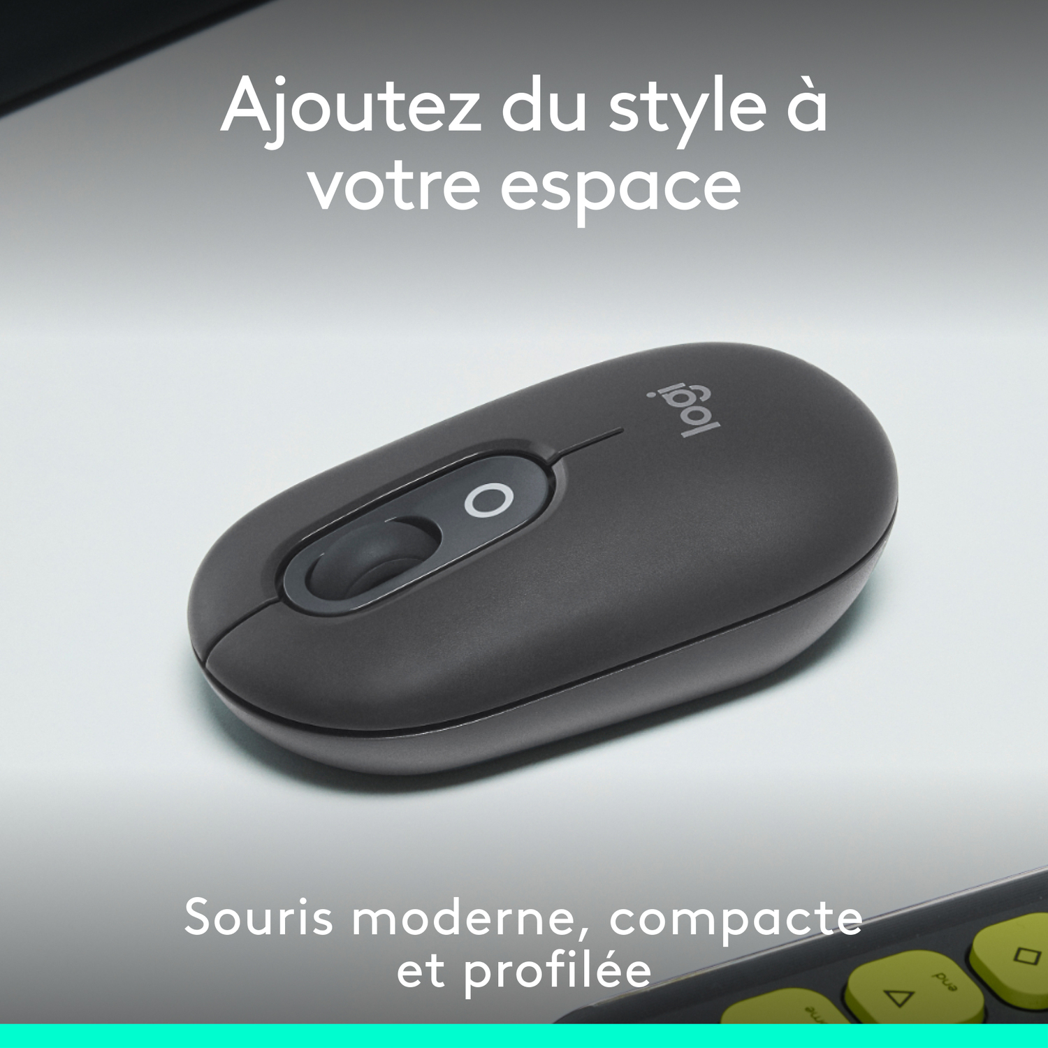 Souris Logitech grise sur une surface blanche. Touches de clavier noires en arrière-plan.
