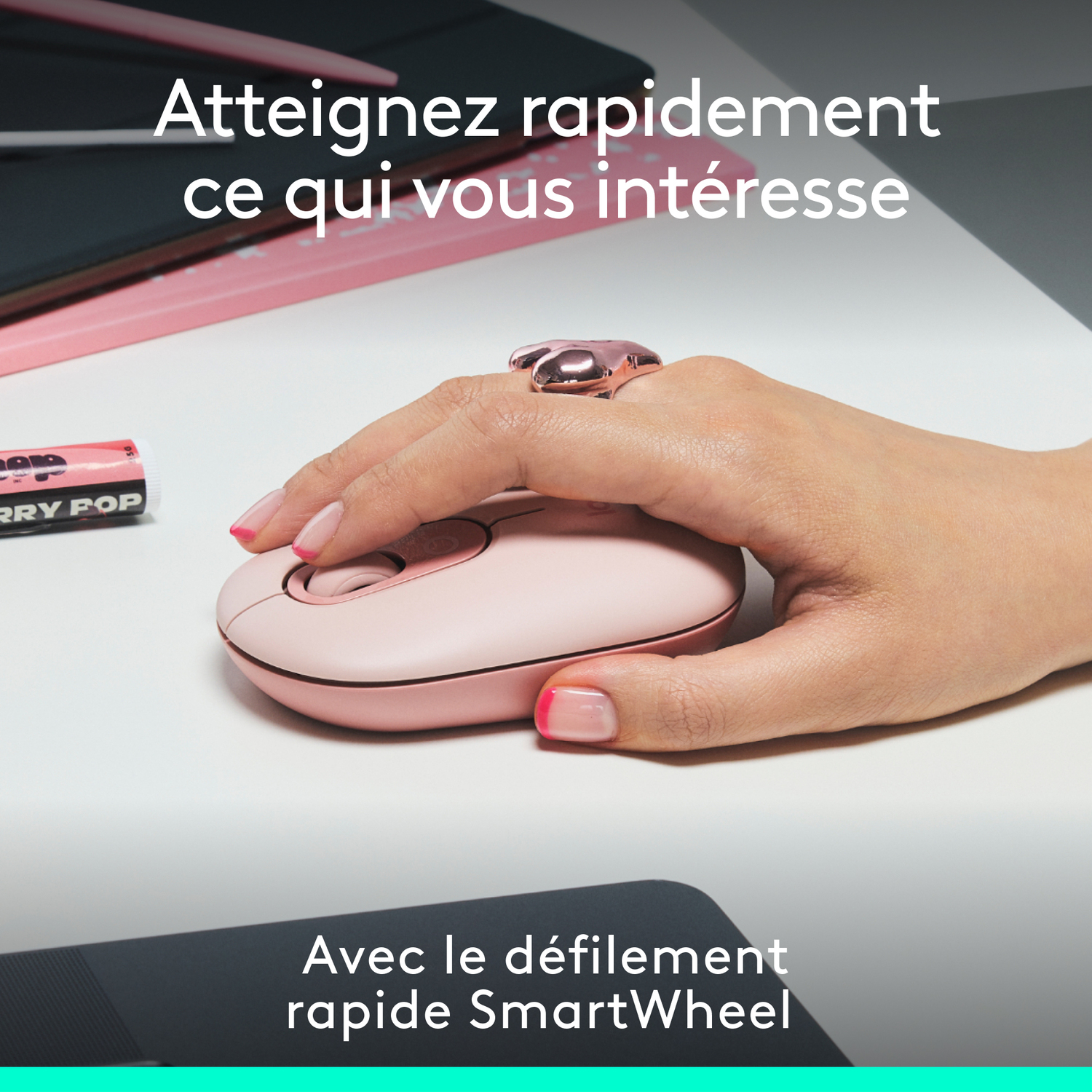 Main avec bague utilisant une souris rose. Texte en français au-dessus de la souris.