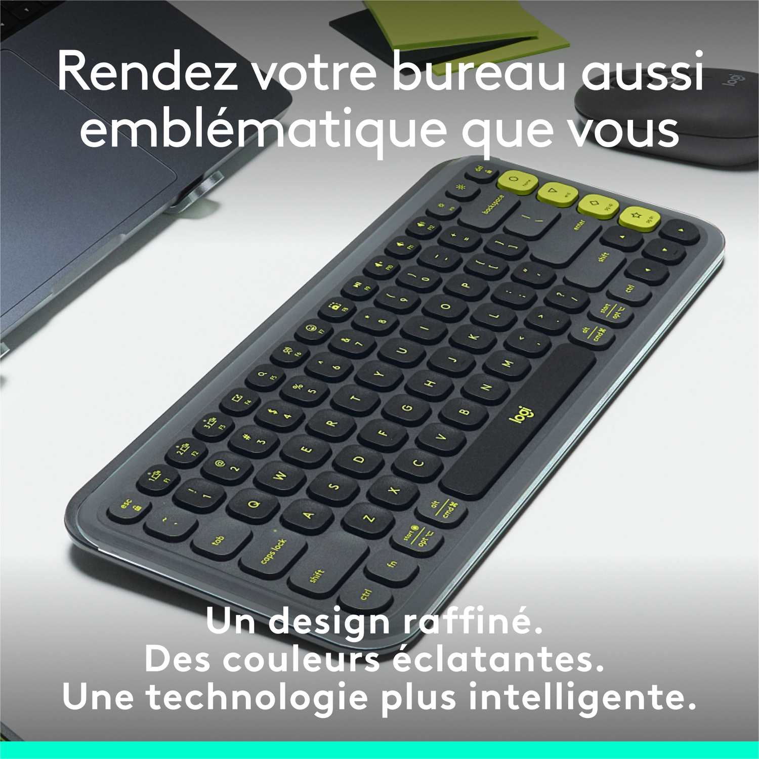Clavier sur un bureau. Les touches sont sombres avec des accents jaunes. Un ordinateur portable et une souris sont à proximité.