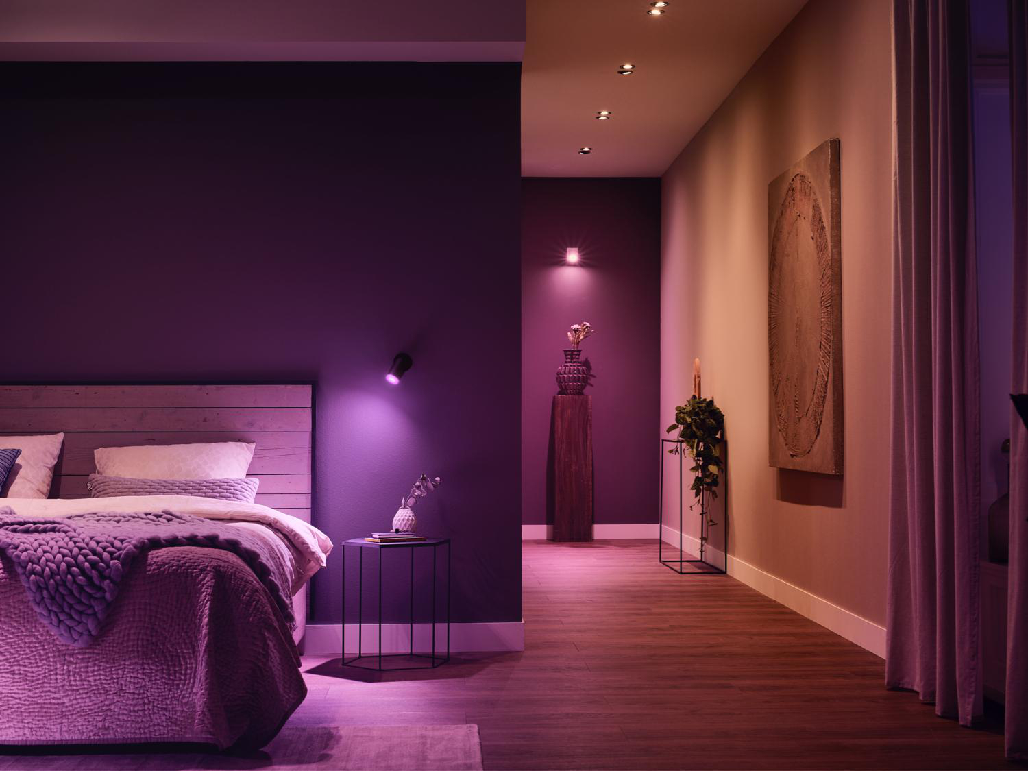 Ein Raum mit einem Schlafzimmer und einem Flur. Das Schlafzimmer hat violettes Licht.