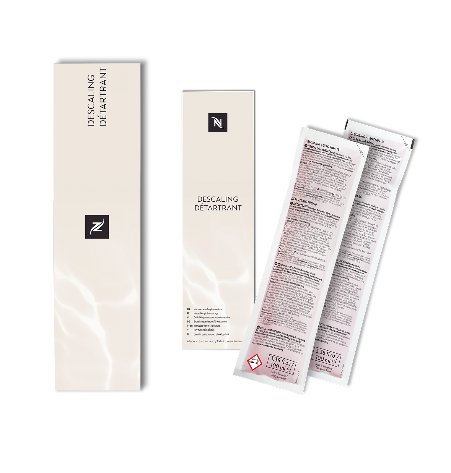 Drei Nespresso-Entkalkungslösungsboxen und zwei Päckchen Entkalkungslösung auf weißem Hintergrund.