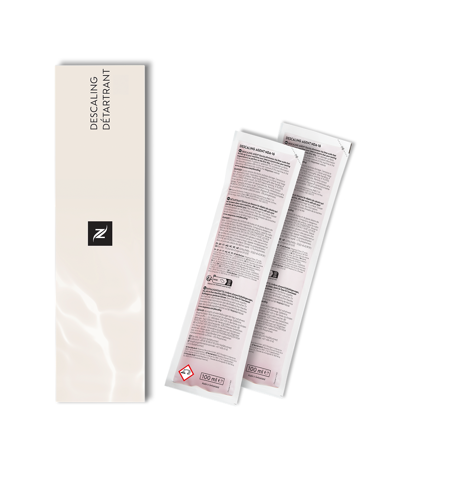 Zwei Nespresso Entkalkungspäckchen neben einer Box mit Text, auf dunklem Hintergrund.