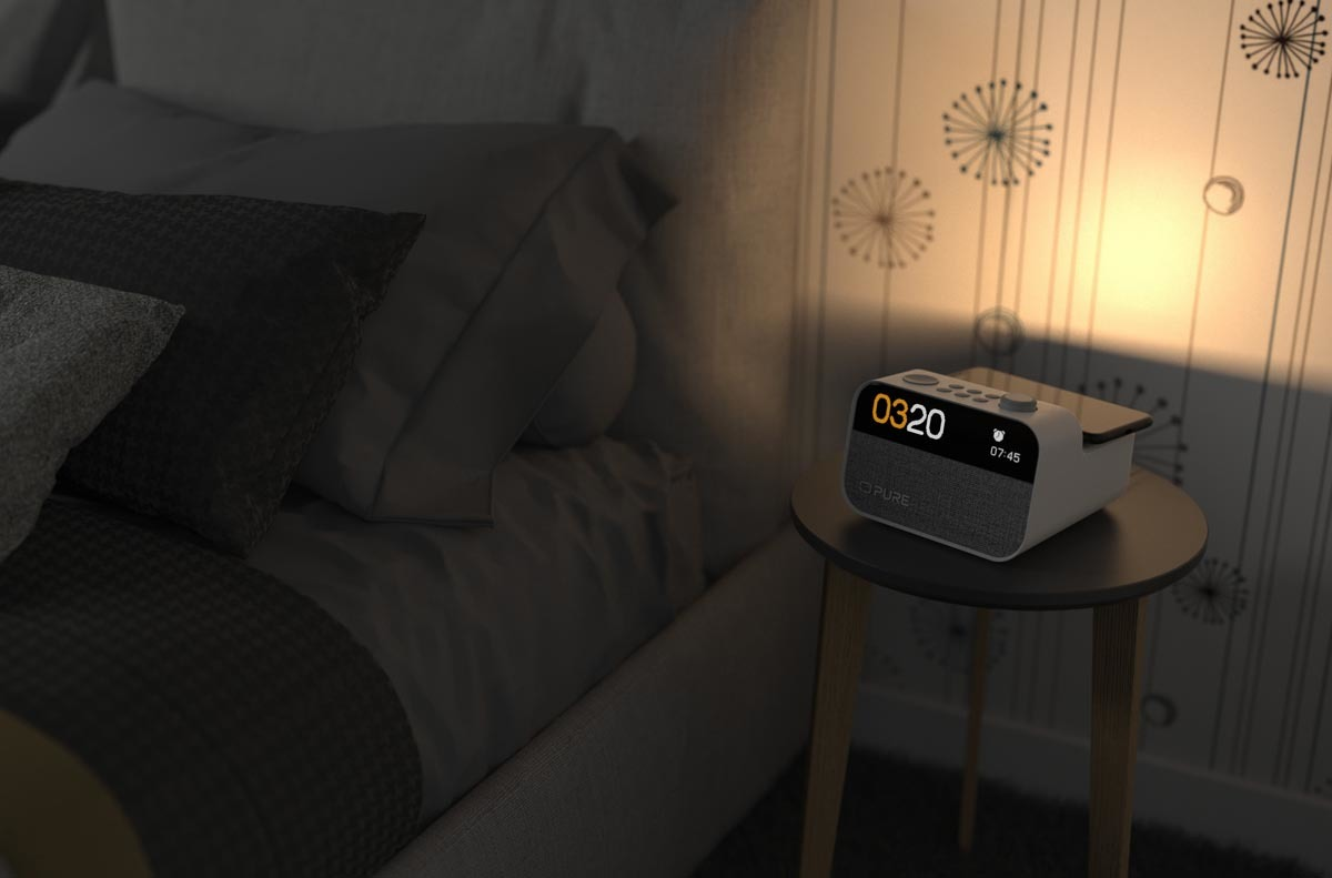 Scène de chambre à coucher la nuit. Un radio-réveil sur une table à côté d'un lit et une lampe.