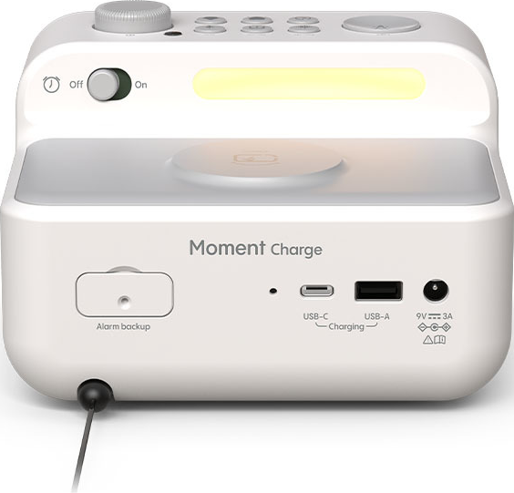 Réveil numérique blanc avec socle de chargement, boutons, écran et ports USB, sur fond blanc.