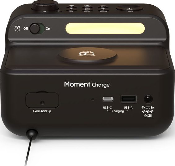Réveil noir avec une lumière en haut, un bouton 'on' et des ports USB sur le panneau avant.
