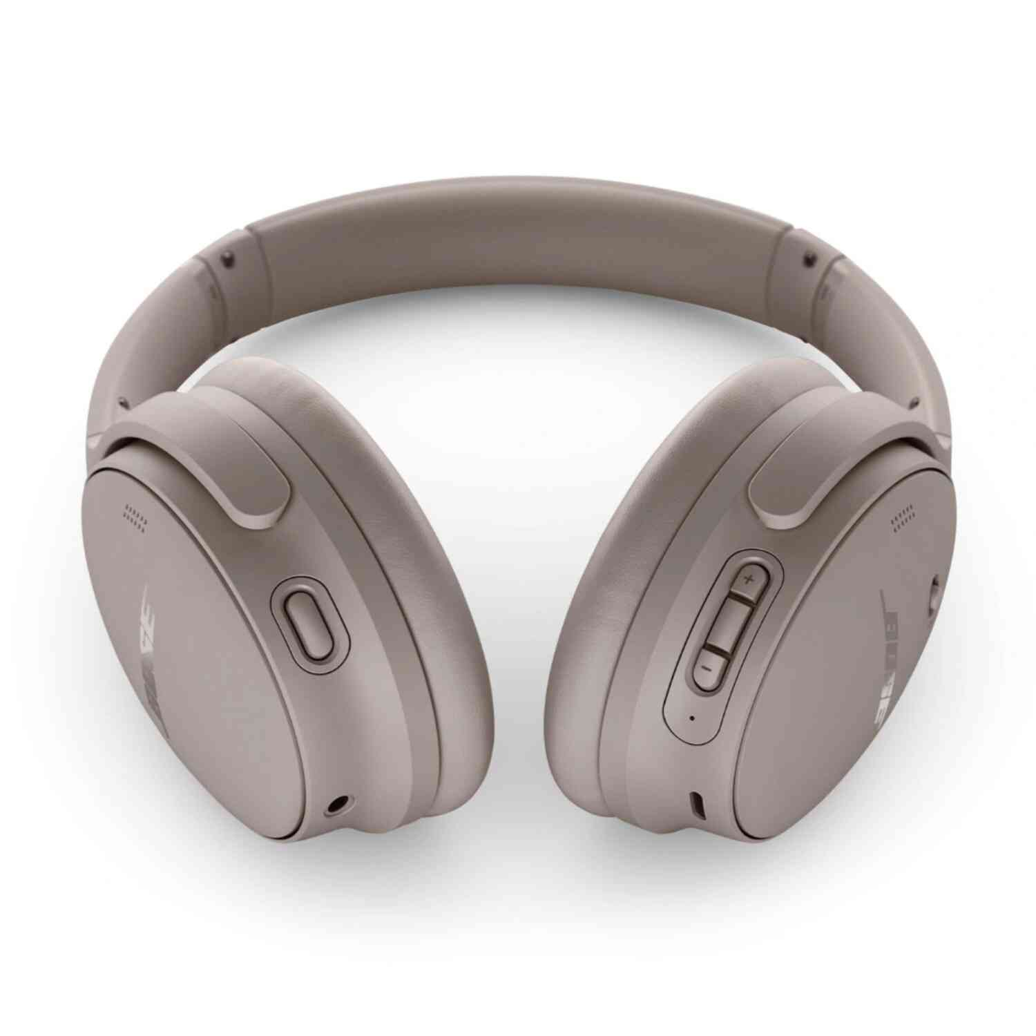 Close-up of taupe headphones with controls on the right earcup, lying on a white surface.