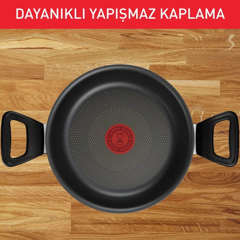 Ahşap bir yüzey üzerinde kırmızı ve siyah kulplu siyah bir tava.