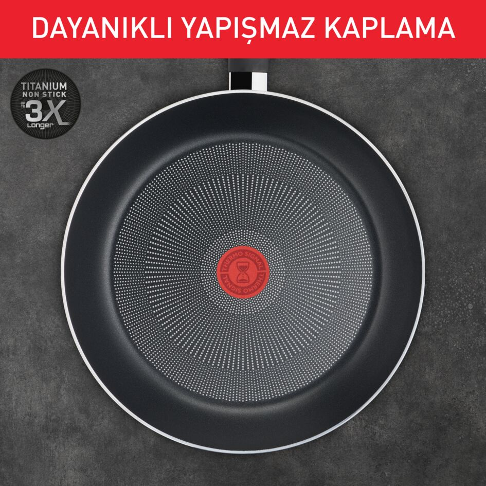 Tefal tava, siyah, beyaz noktalı iç kısım ve ortada kırmızı daire.