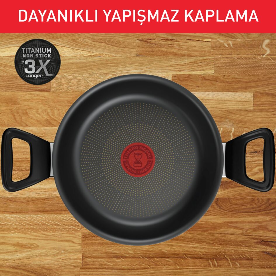 Ahşap masada saplı bir tava, yukarıdan görünüm. Tava siyahtır.