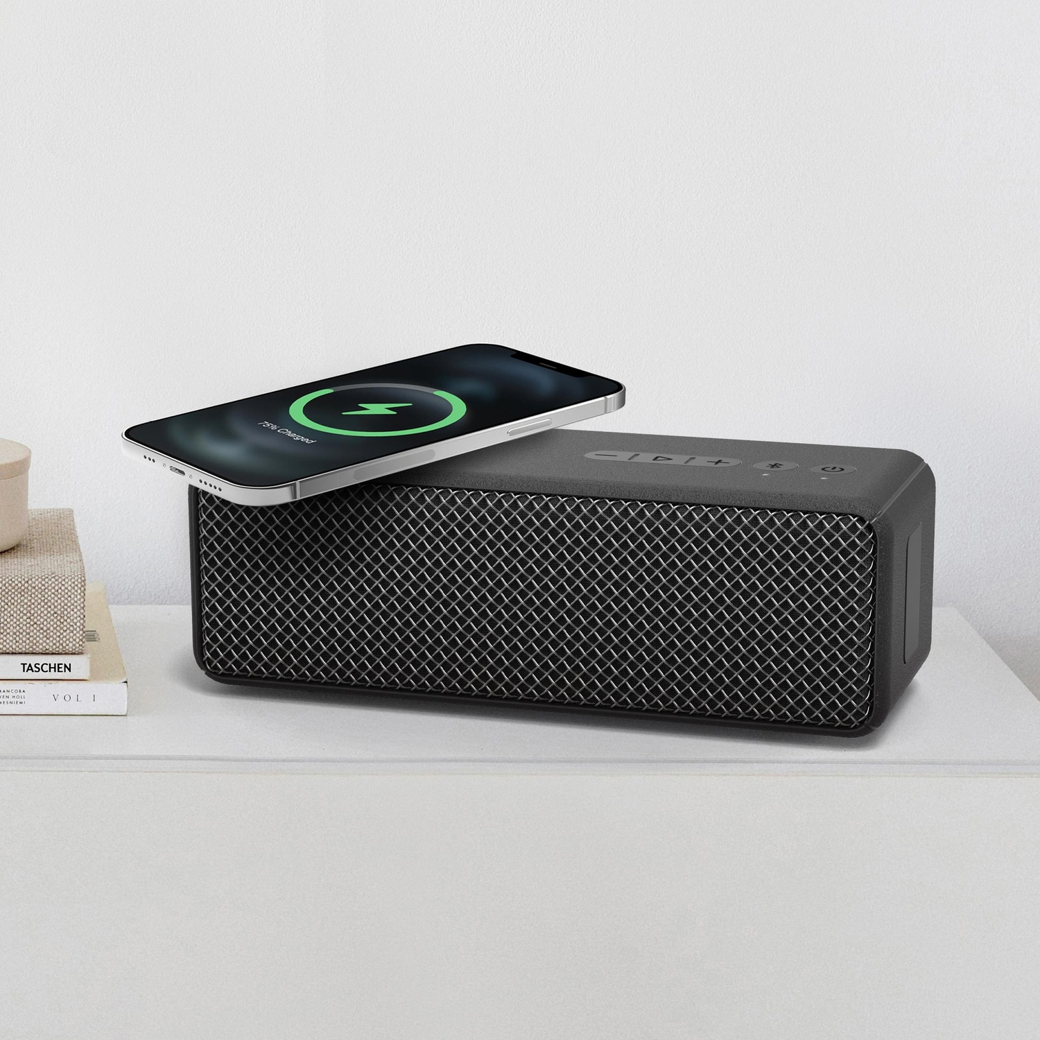 Altoparlante nero con telefono in carica sopra e tavolo bianco. Testo: 99% Carico.