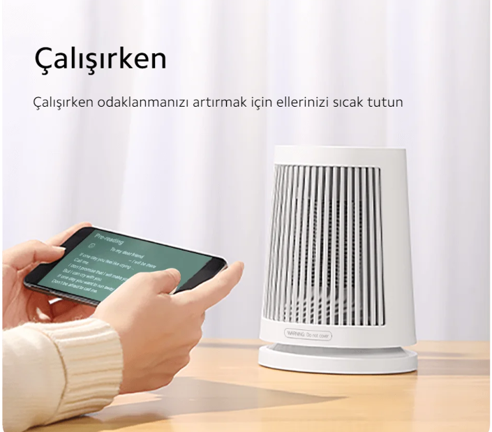 Küçük beyaz bir ısıtıcı ile bir el telefon tutuyor.