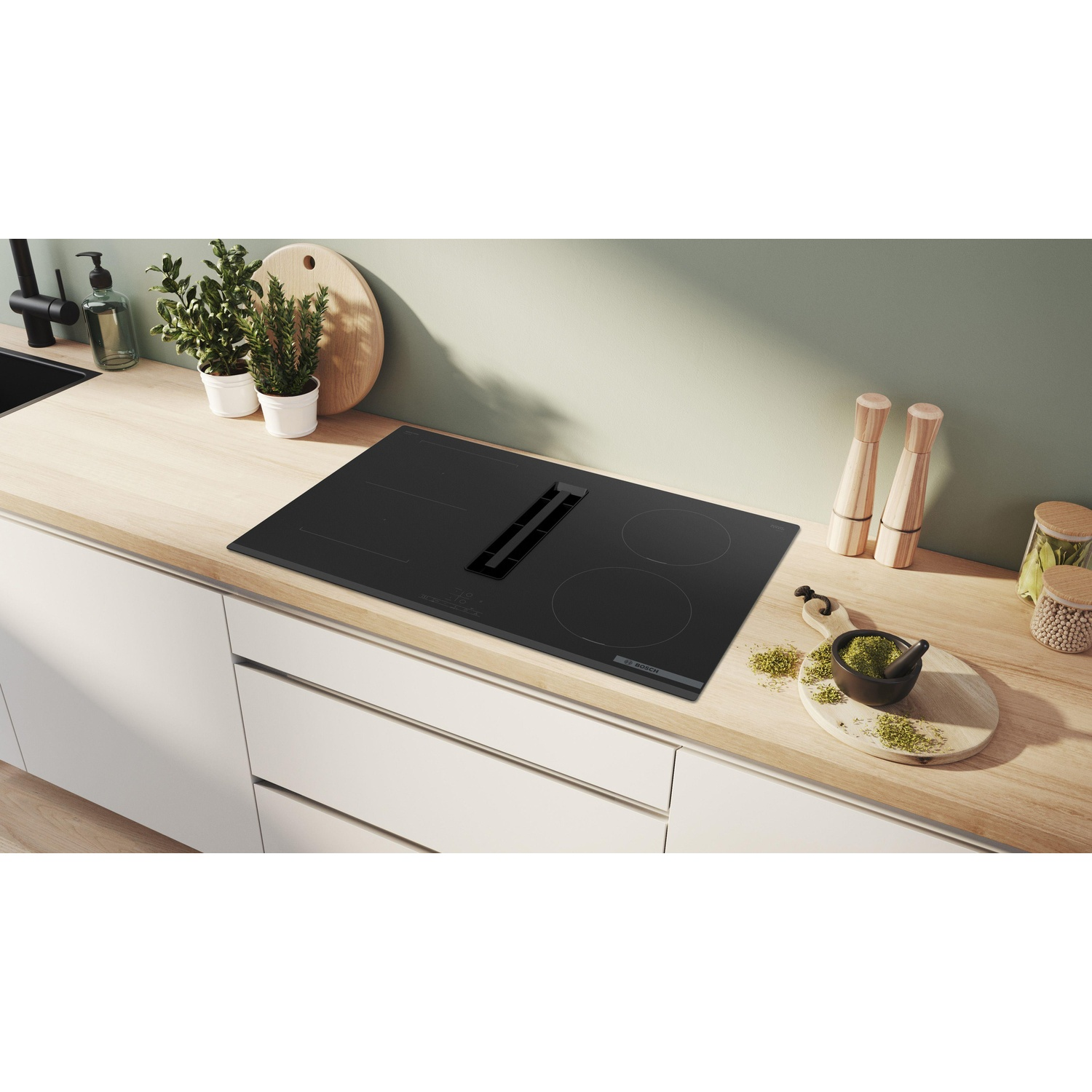 Piano cottura nero con ventilazione integrata, su un piano di lavoro in legno con decorazioni.