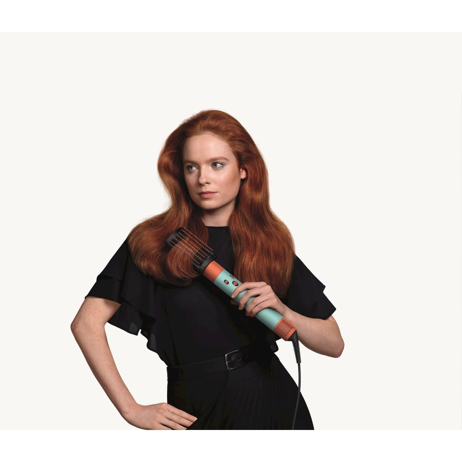 Donna con i capelli rossi che tiene una spazzola per capelli.