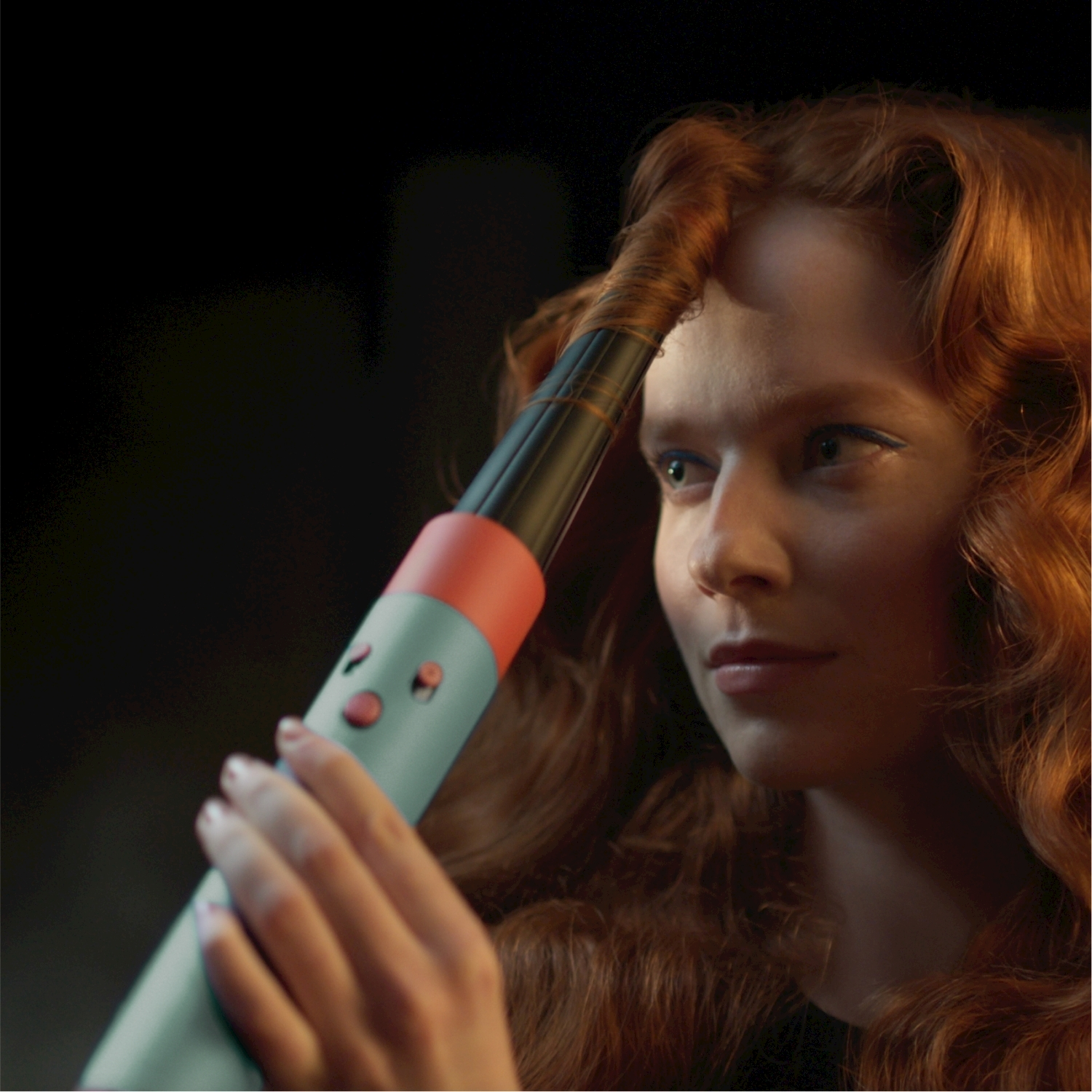 Donna con capelli rossi che si arriccia i capelli con un ferro arricciacapelli turchese.