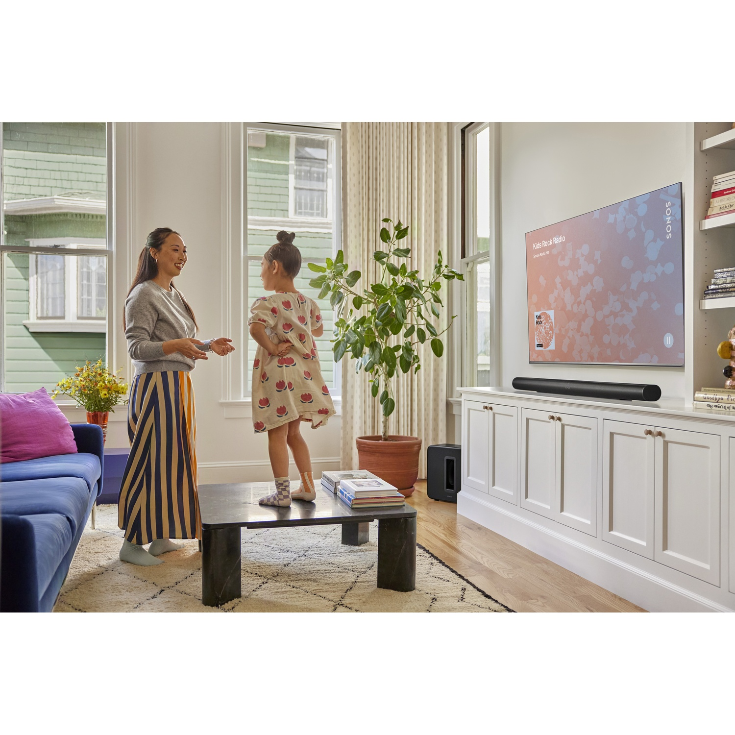 Un soggiorno con due donne, una tv, una soundbar, un subwoofer e un tavolino.