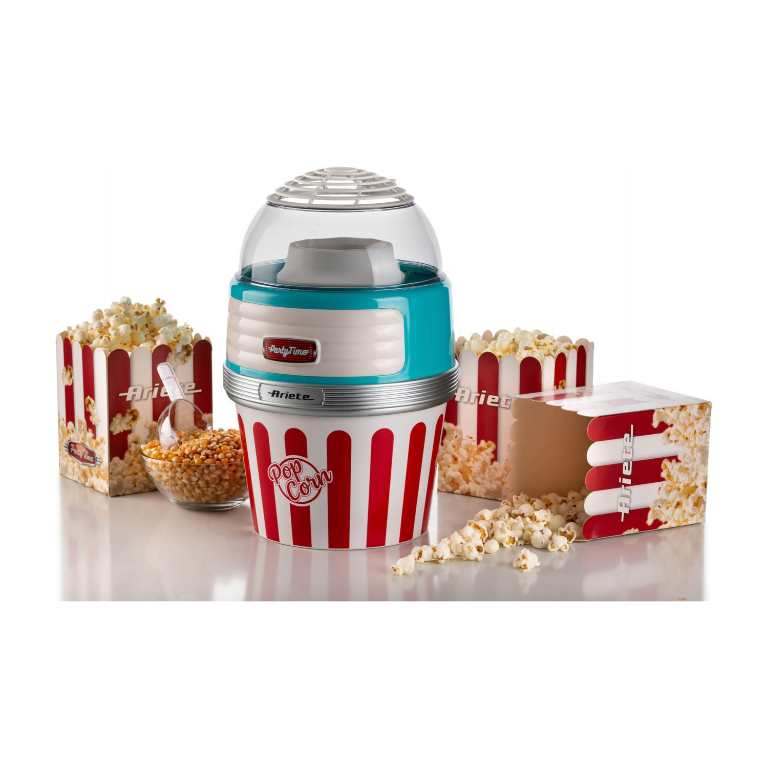 Macchina per popcorn con popcorn e chicchi, e scatole di popcorn su una superficie bianca.