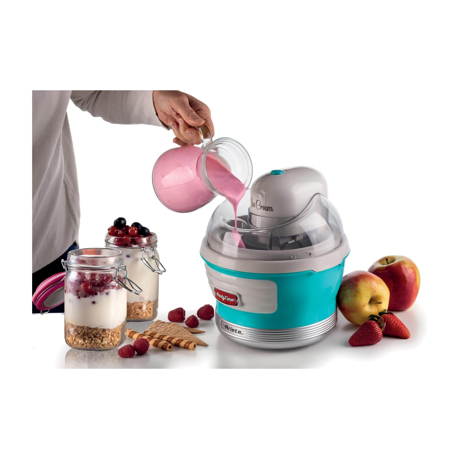 Una gelatiera con liquido rosa che vi si versa. Vasi di bacche e frutta a lato.