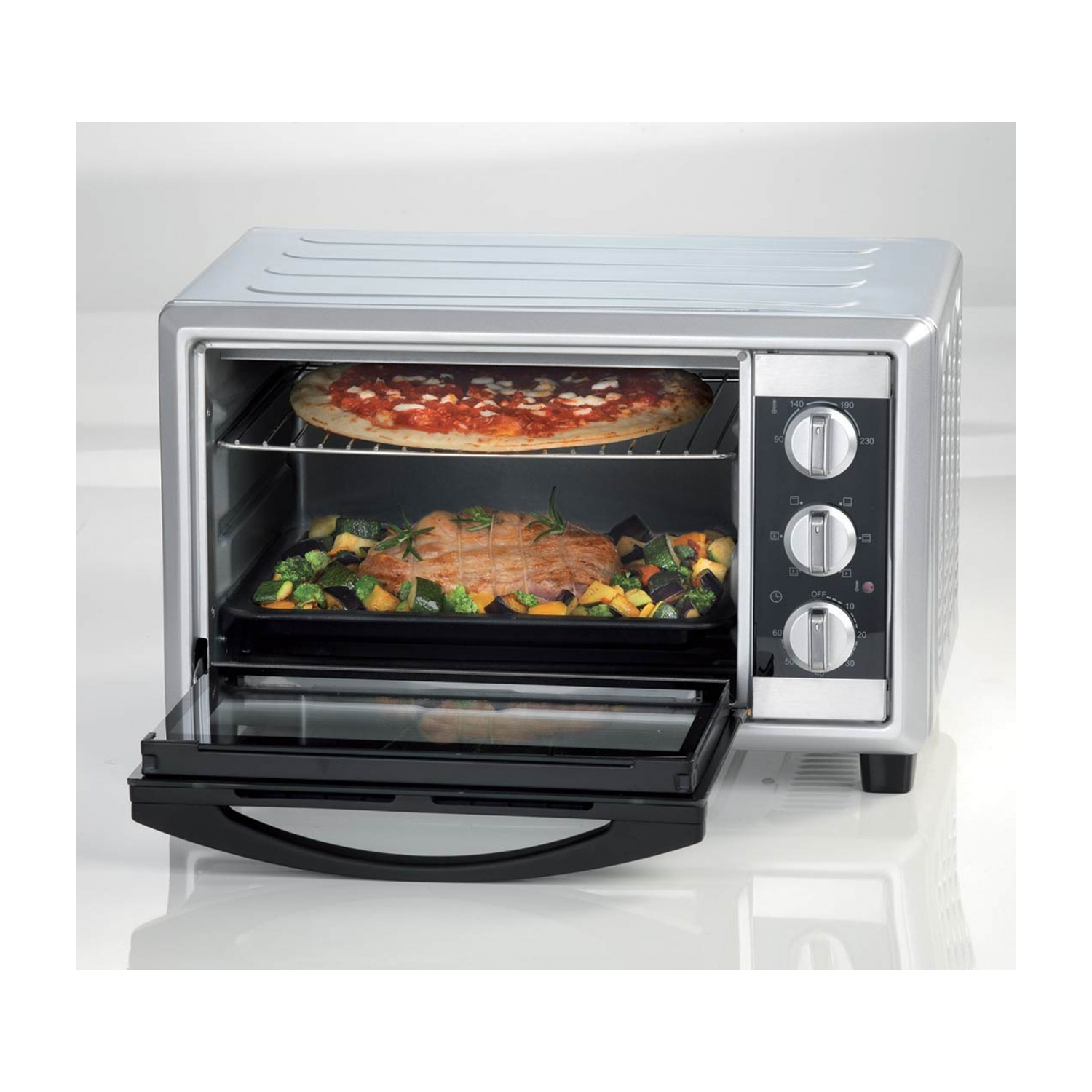 Un forno argentato con la porta aperta, che mostra una pizza e verdure. Il forno è su sfondo bianco.