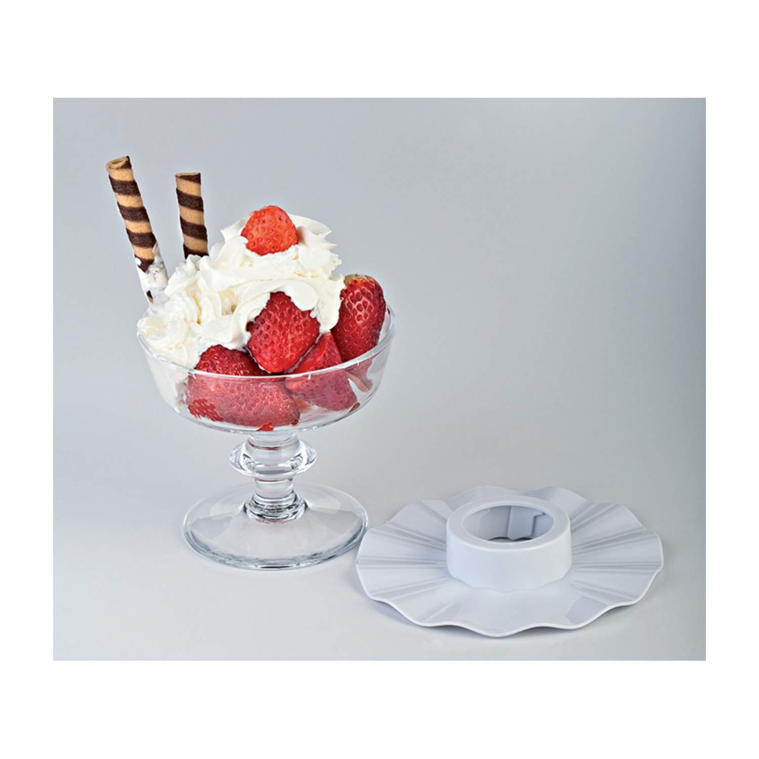 Coppa di gelato con panna montata, fragole e wafer in un bicchiere trasparente.