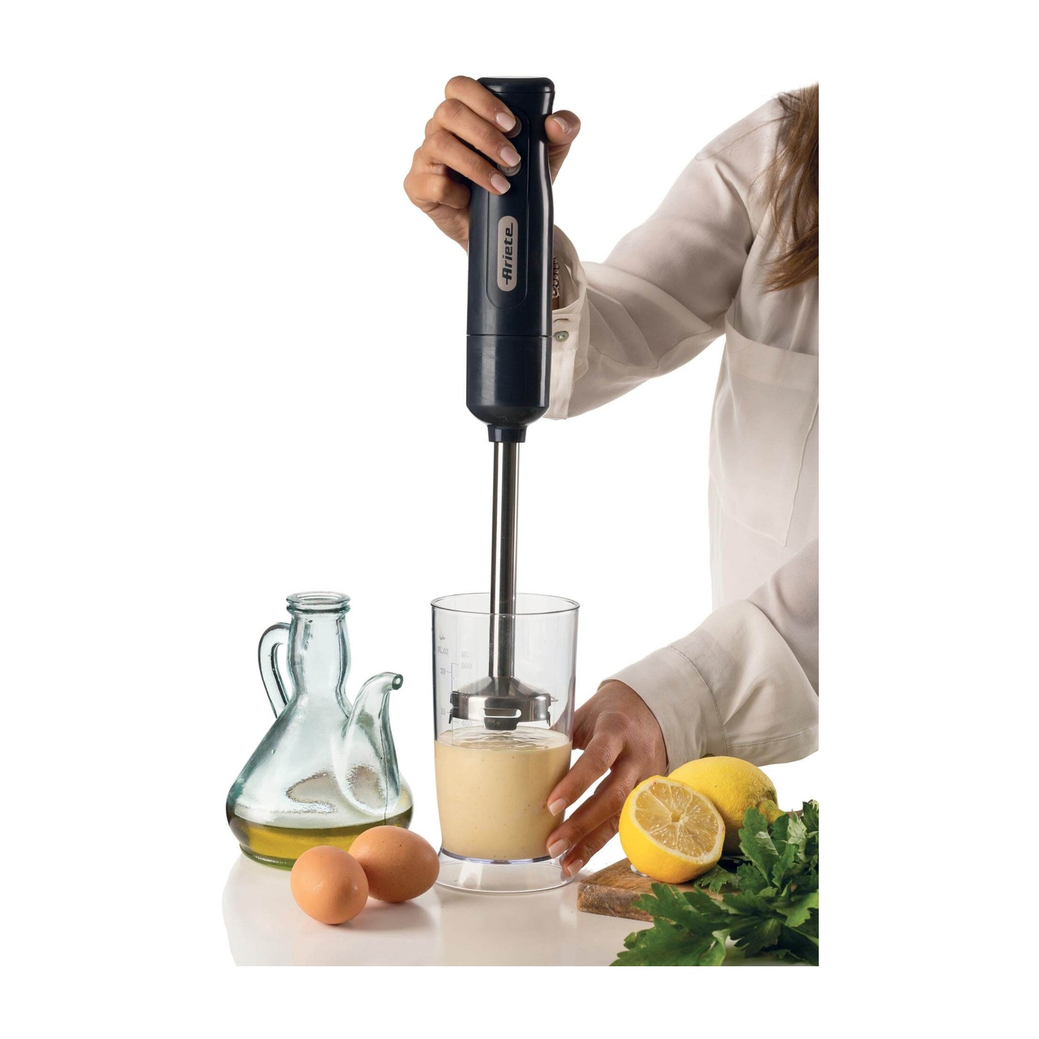 Una persona usa un frullatore a immersione per mescolare gli ingredienti in un bicchiere. Ingredienti: uova e limone.