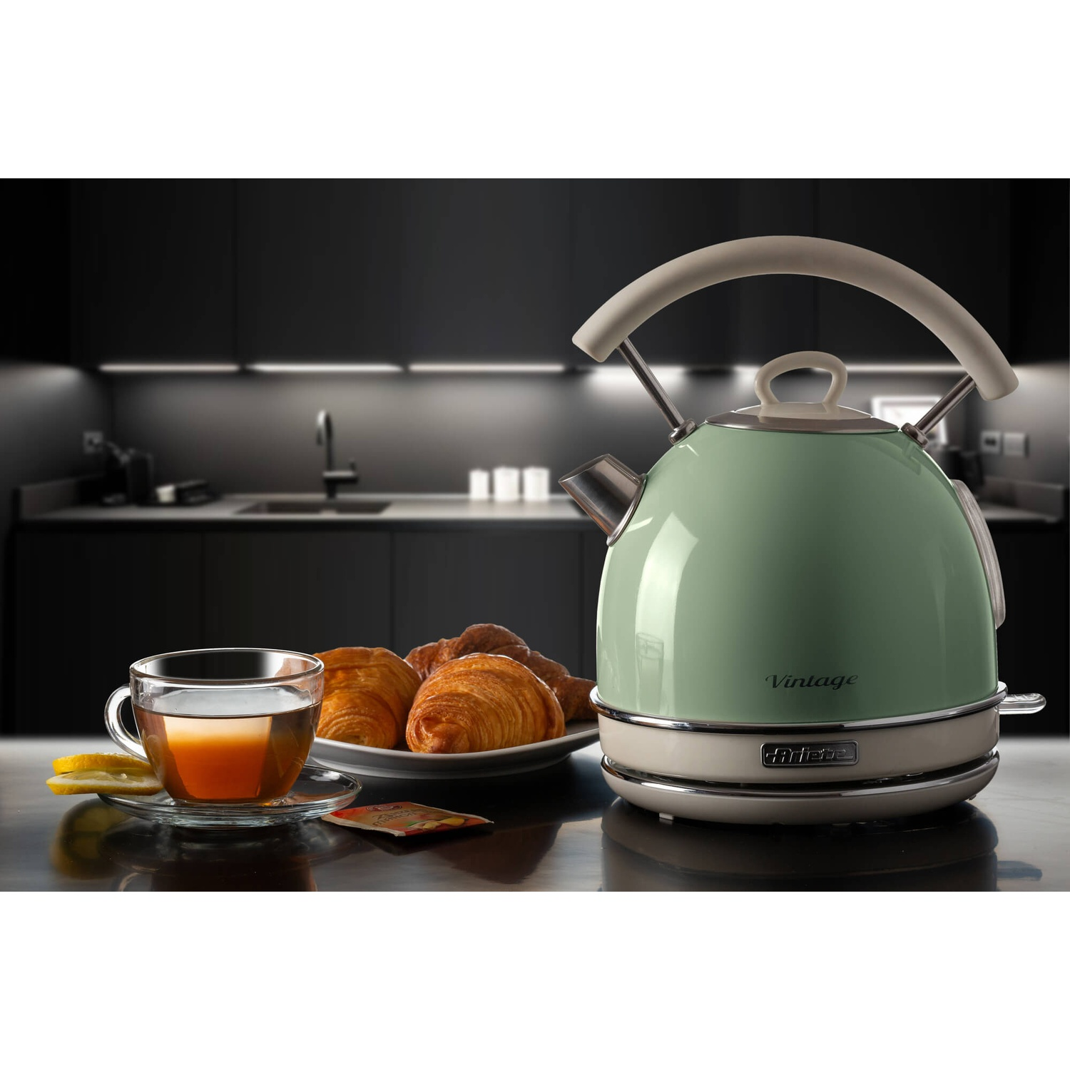 Un bollitore verde con un piatto di croissant e una tazza di tè.