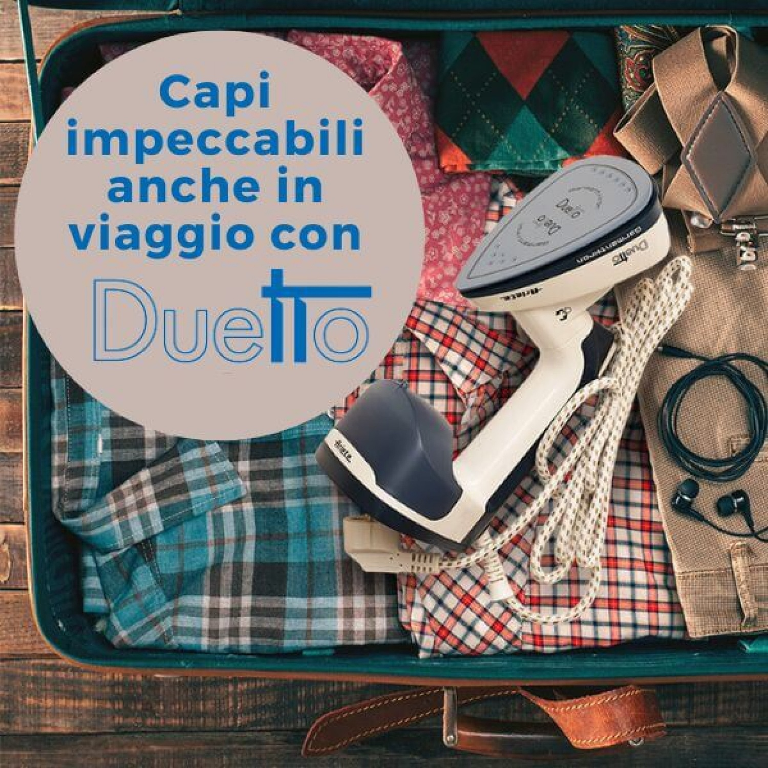 Un ferro da viaggio con accessori in una valigia aperta su una superficie di legno.