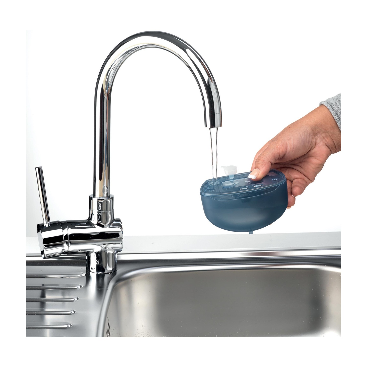 Una mano che tiene un dispositivo blu scuro sotto un rubinetto d'argento con acqua corrente.