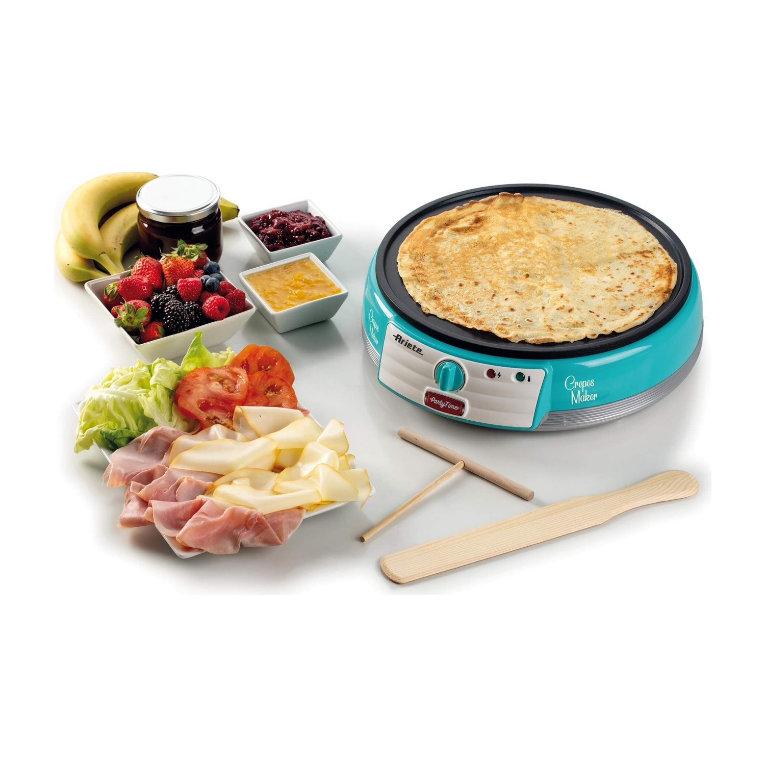 Macchina per crepes con una crepe sopra, circondata da ingredienti come frutta e prosciutto.