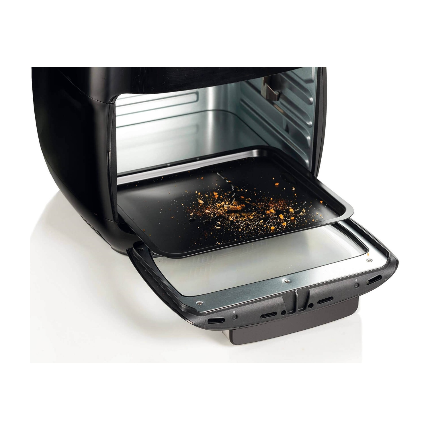 Forno friggitrice ad aria nero con vassoio parzialmente estratto, briciole visibili.