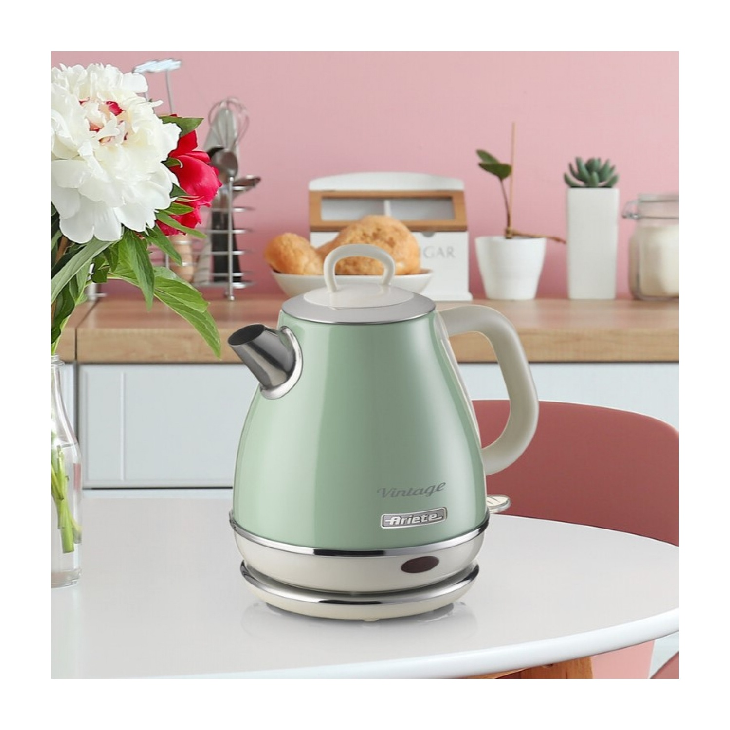 Bollitore elettrico verde su un tavolo bianco con fiori.
