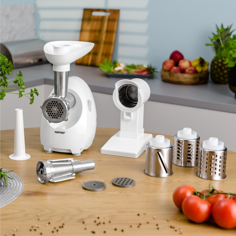 Robot kuchenny z przystawkami. Zawiera maszynkę do mięsa i krajalnice na drewnianej powierzchni.