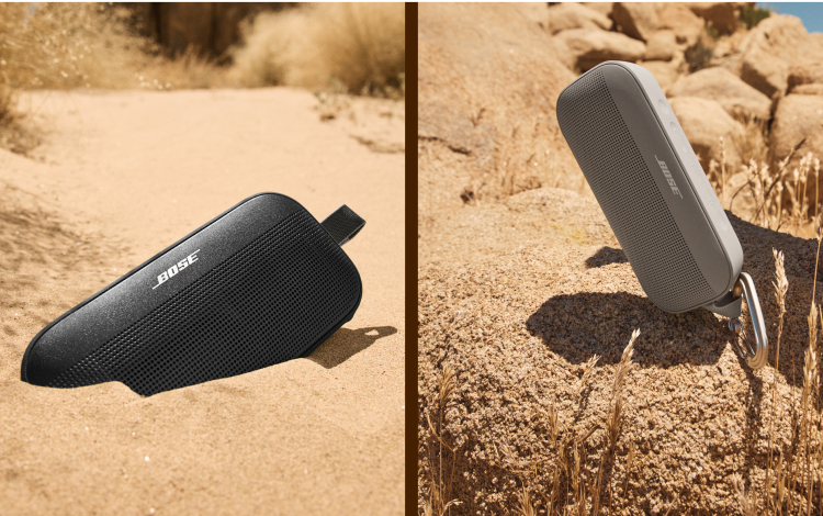Tragbarer Bose-Lautsprecher im Sand und auf einem Felsen, beide mit Bose-Logo.
