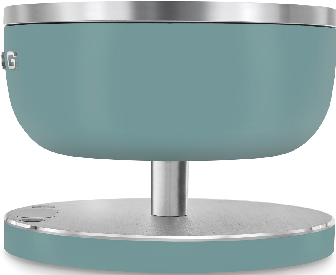 Une balance de cuisine turquoise sur une base argentée. Elle a un affichage circulaire et des boutons.