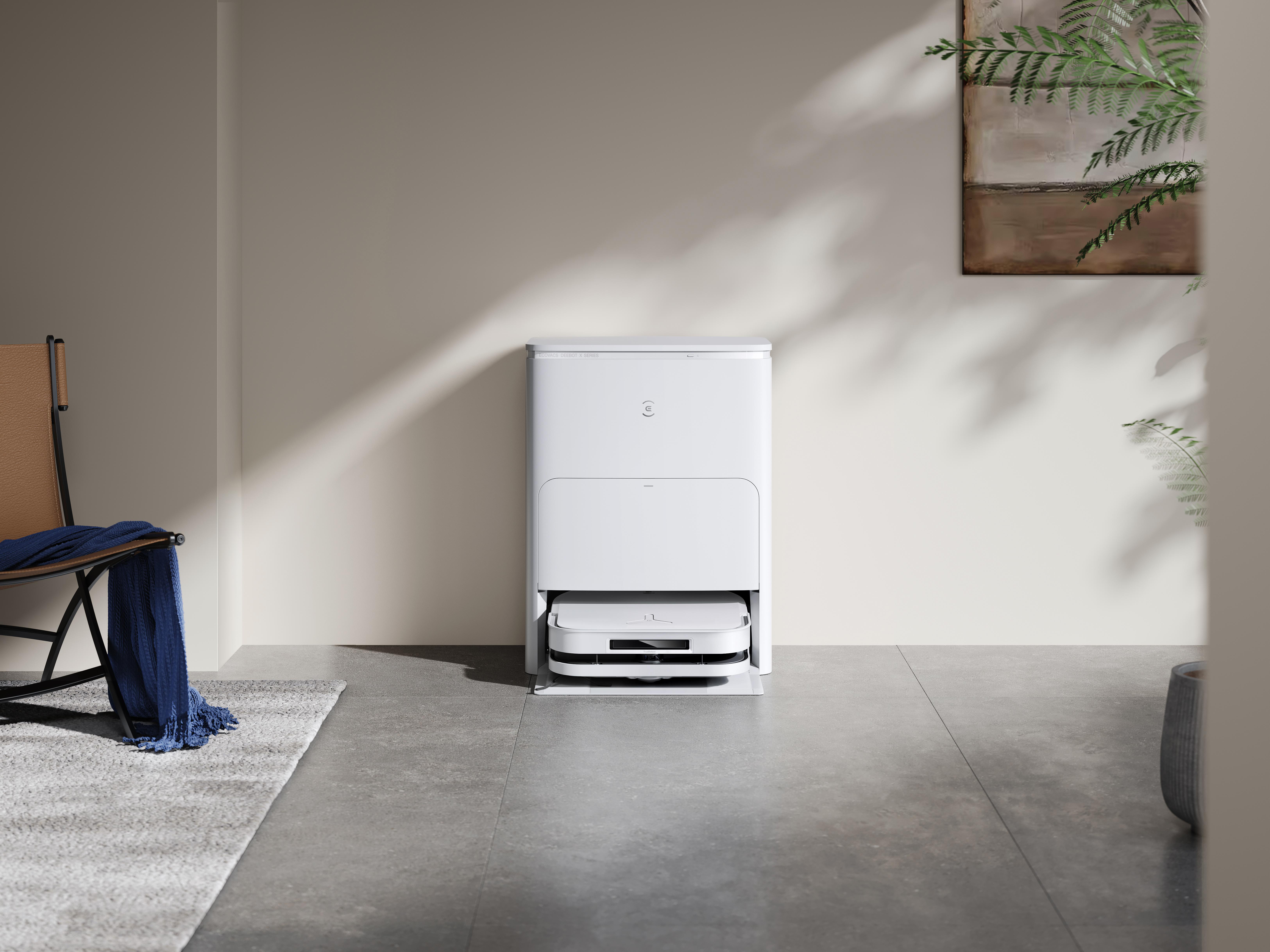 Ein weißer Roboter-Staubsauger und seine Basisstation in einem modernen Wohnzimmer.