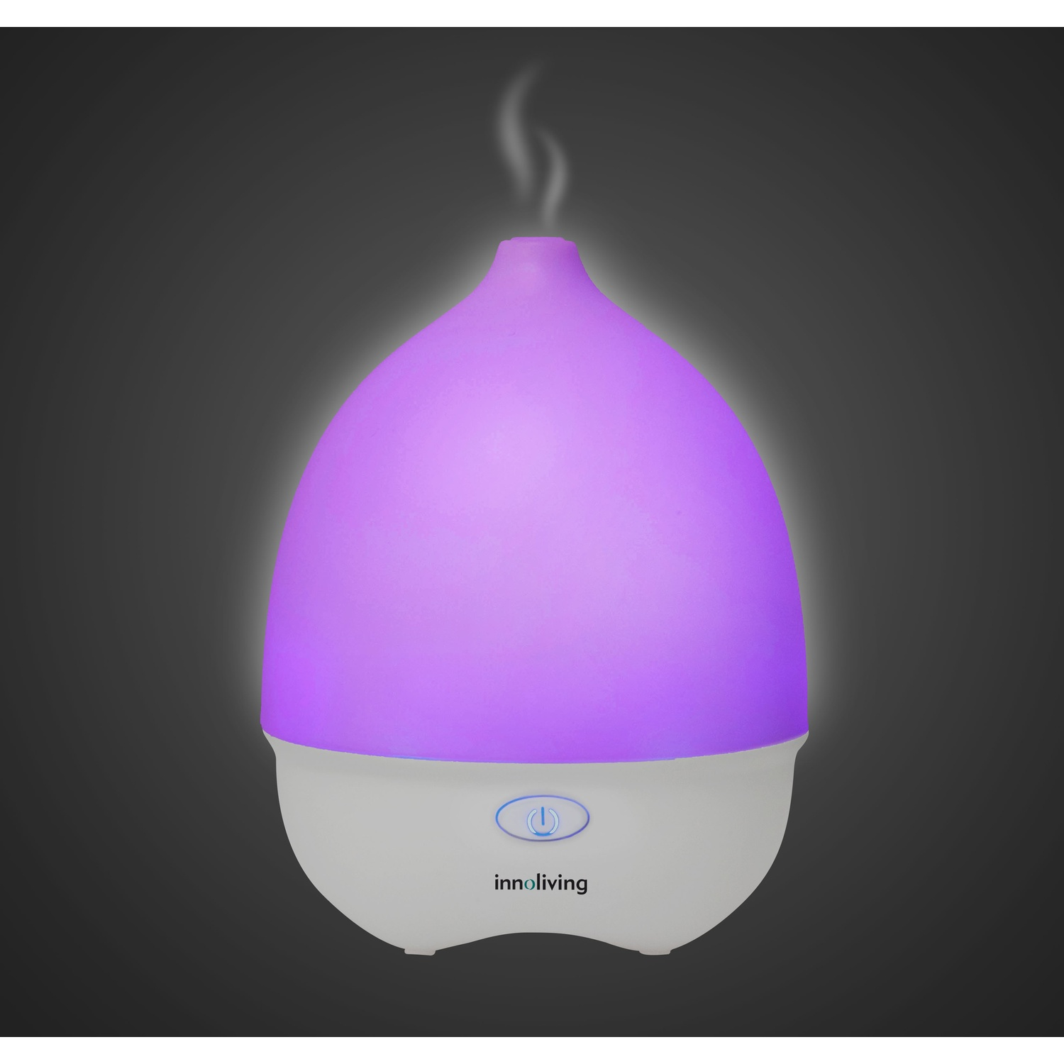 Un diffusore di oli essenziali bianco e viola illuminato, con vapore che esce. Sfondo grigio scuro.