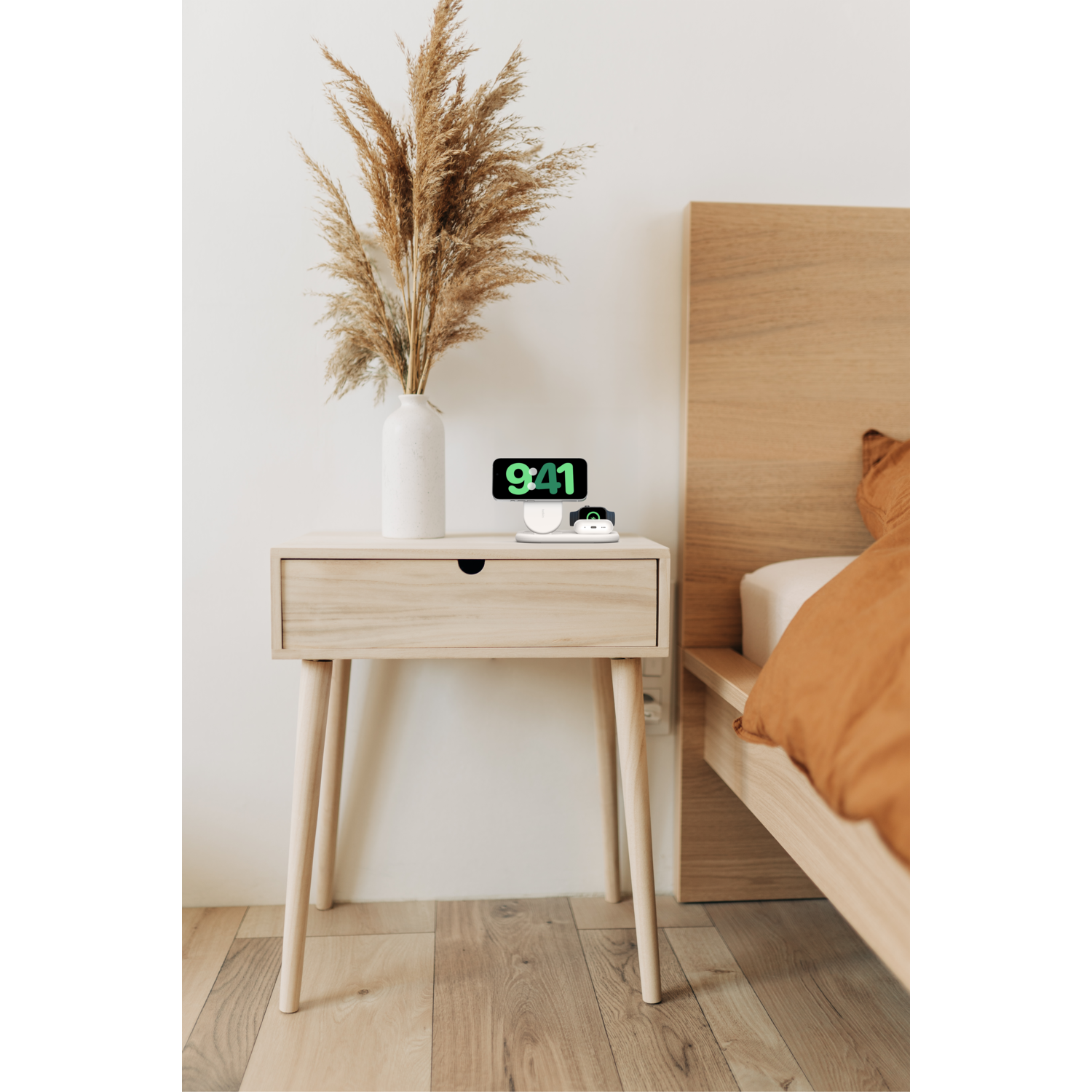 Table de chevet avec vase, téléphone et chargeur.