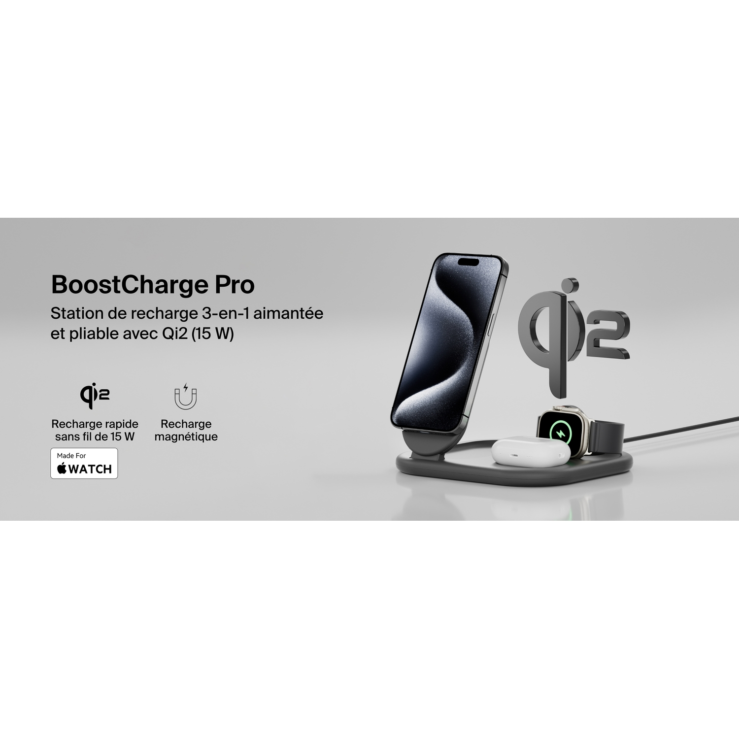 Station de charge noire et argentée. Elle charge un téléphone, une montre et des écouteurs sur surface blanche.