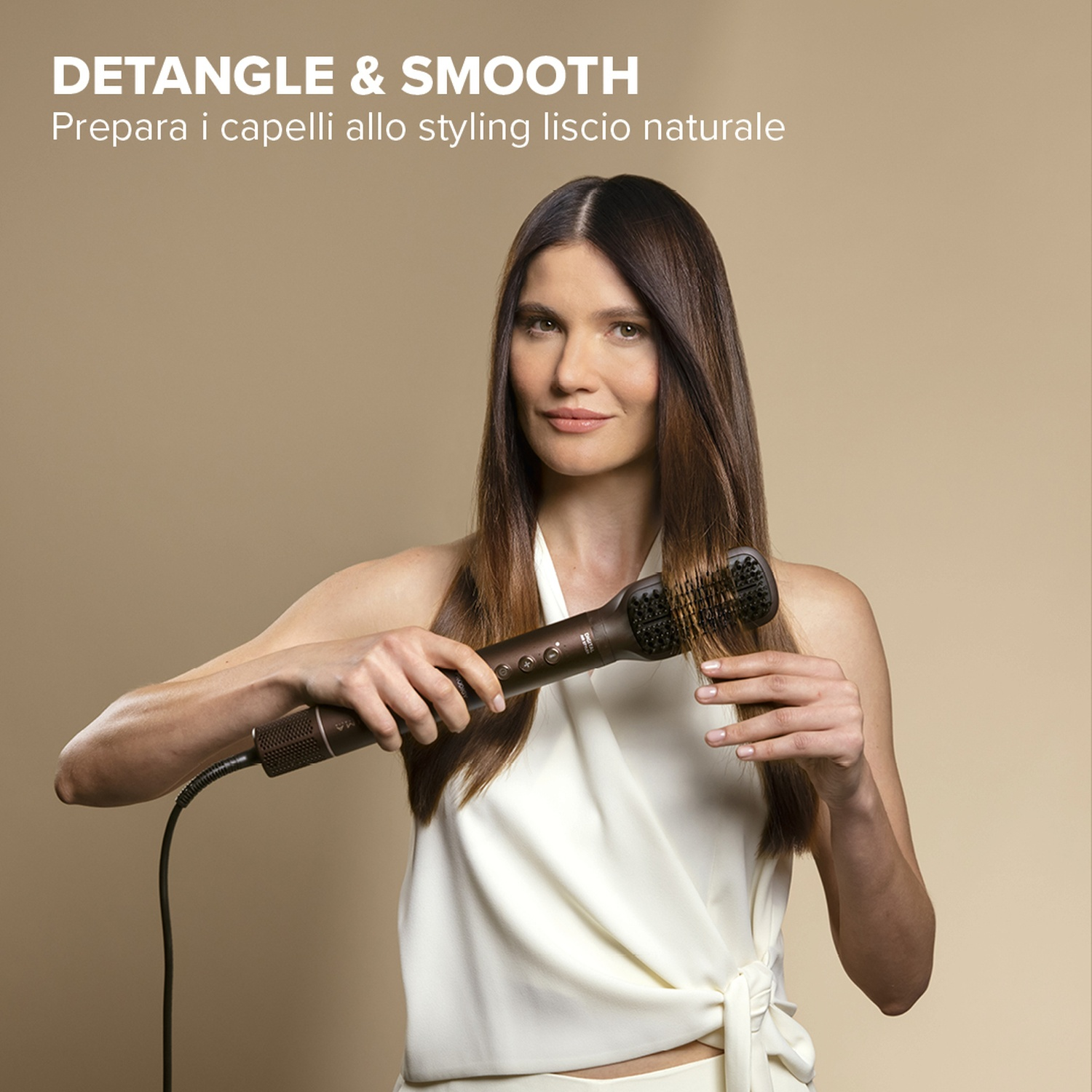 Una donna districa i capelli con una spazzola, sorridendo alla fotocamera.