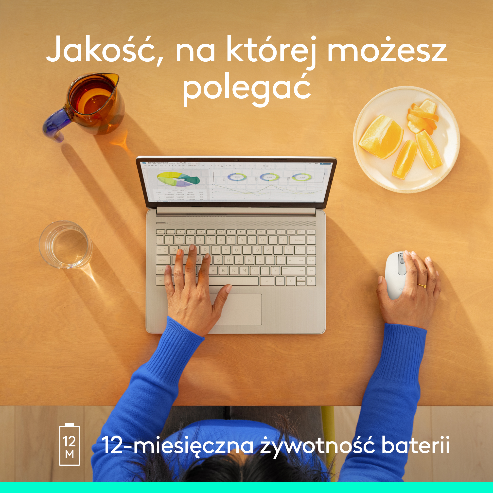 Laptop otwarty na drewnianym stole z przedmiotami wokół, ręce używają klawiatury i myszy.