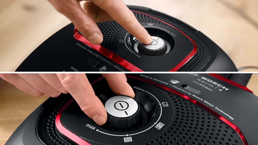 Zbliżenie odkurzacza z dwiema rękami wchodzącymi w interakcję z panelem sterowania.