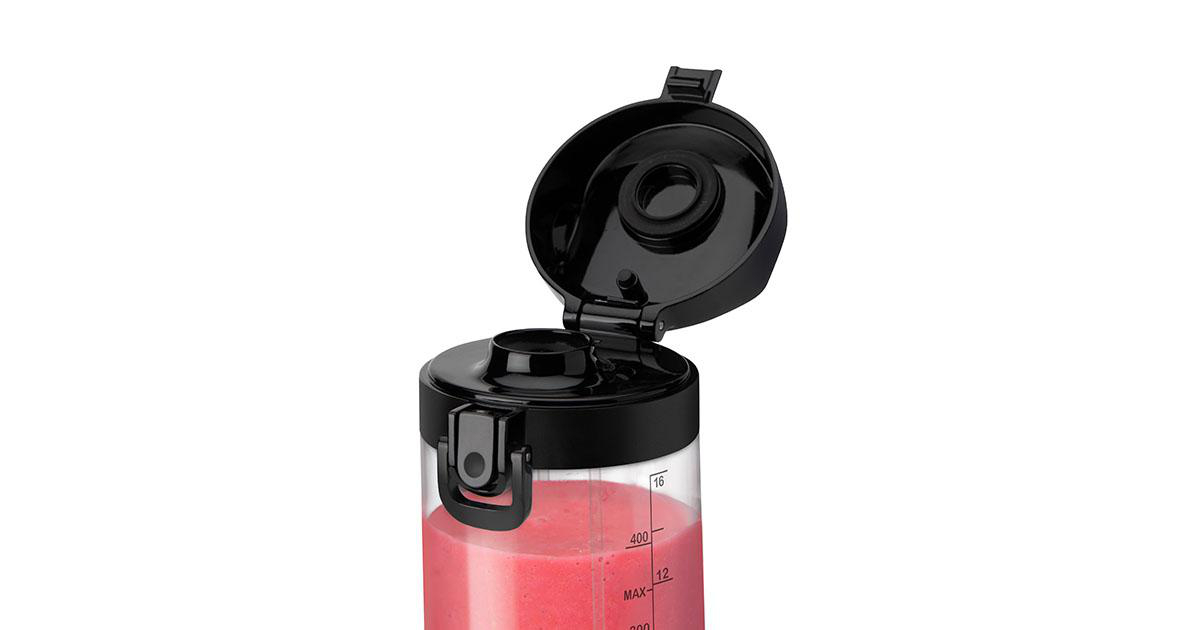 Eine transparente Mixerflasche mit rosa Flüssigkeit, schwarzem Deckel offen und Markierungen.