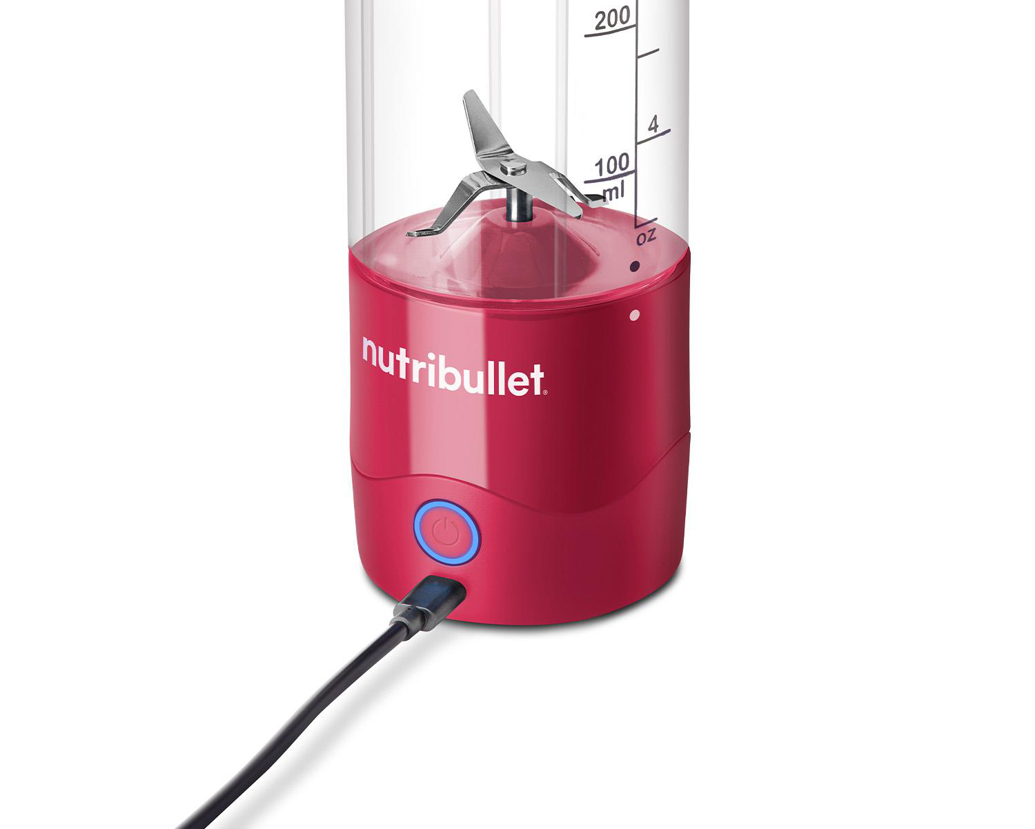 Ein roter Nutribullet-Mixer mit einem transparenten Behälter, der an eine Stromquelle angeschlossen ist.