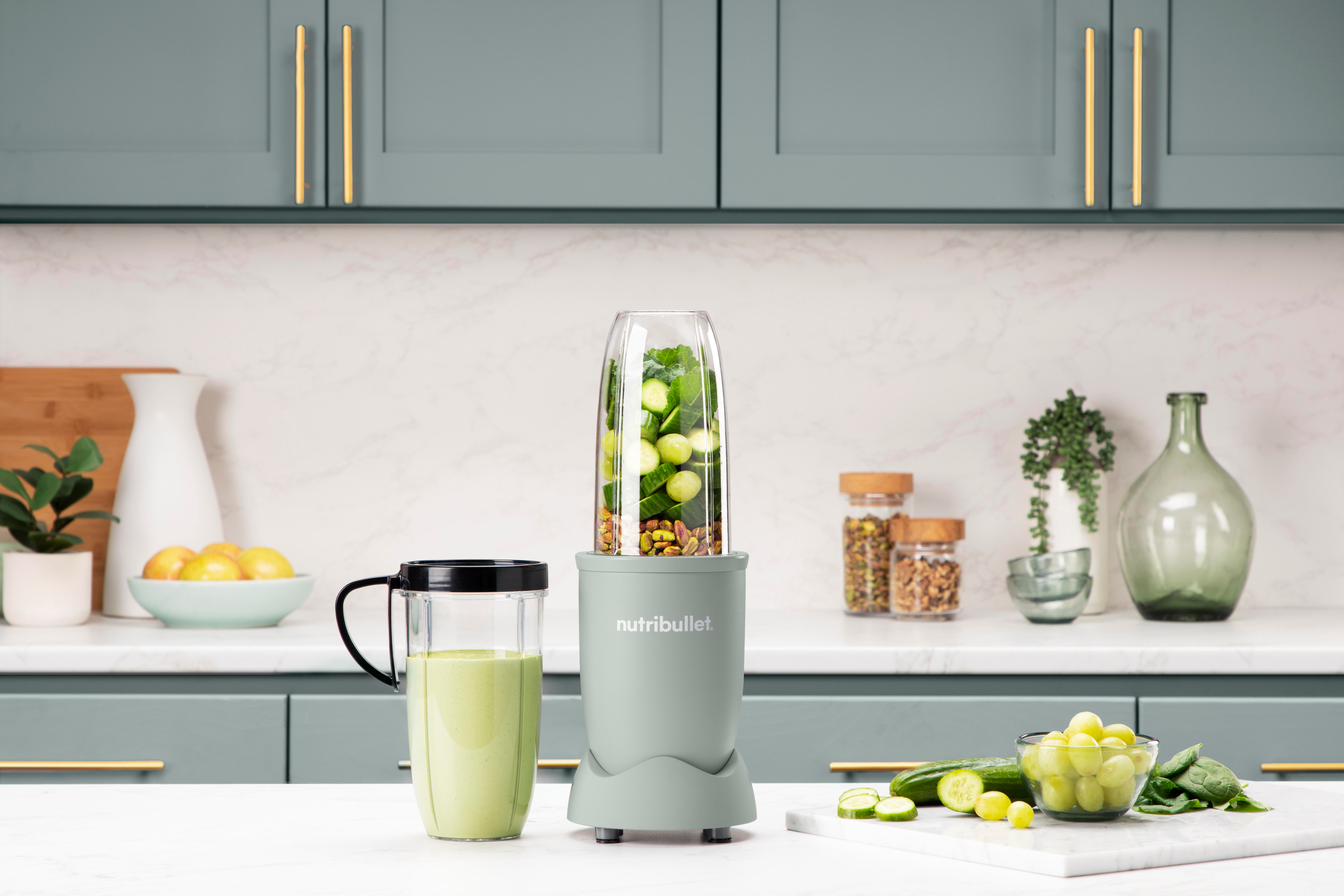 Ein Mixer mit grünen Zutaten, Smoothie und Früchten.
