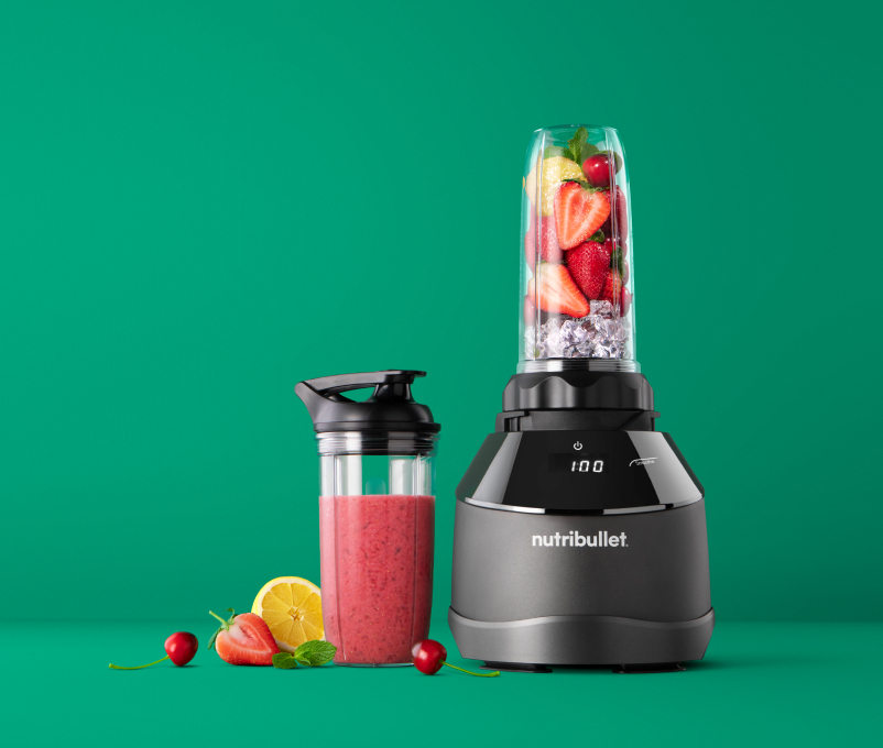 Nutribullet-Mixer mit Früchten und Smoothie. Grüner Hintergrund.