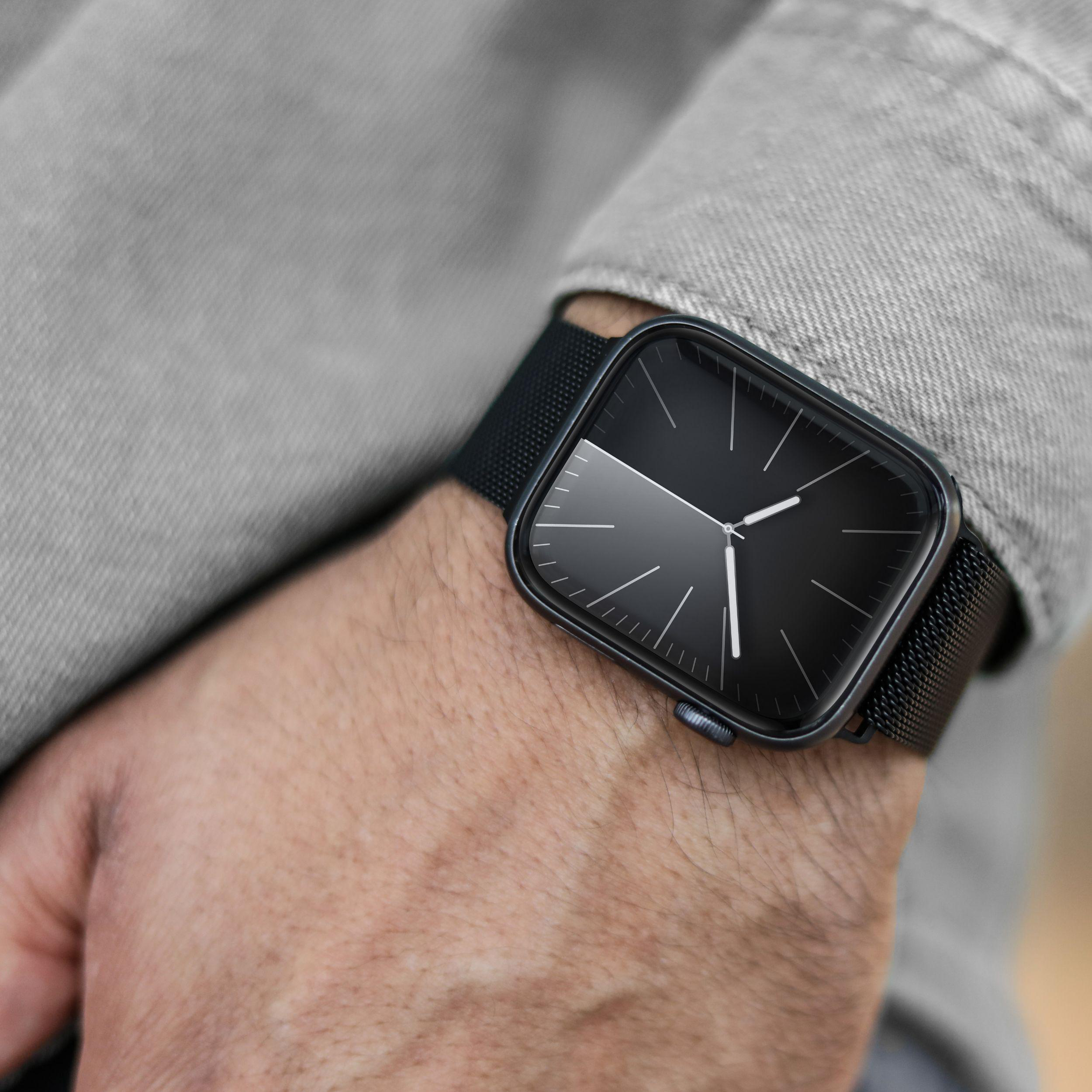 Person trägt schwarze Uhr mit quadratischem Zifferblatt am Handgelenk.