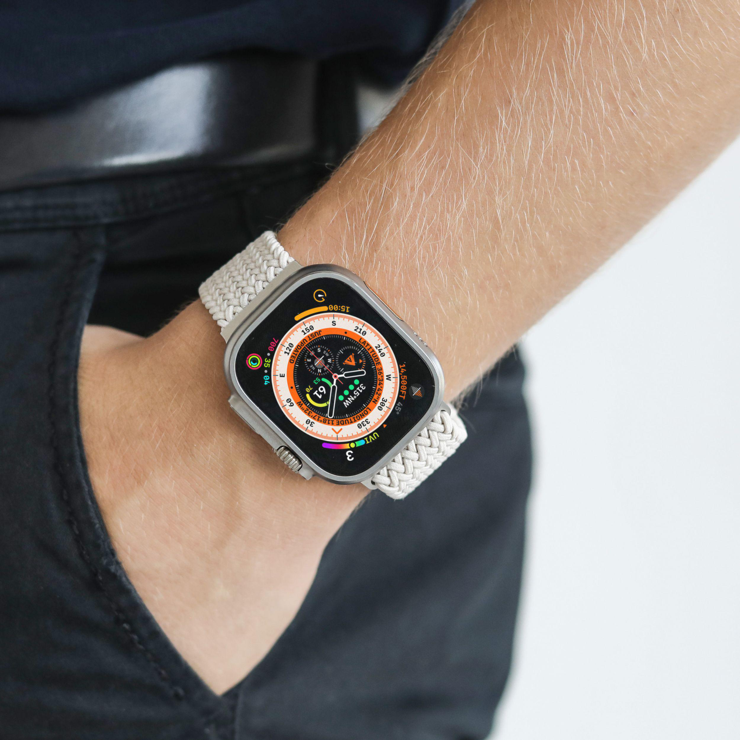 Das Handgelenk einer Person mit einer Smartwatch und einem grau-weißen Armband.