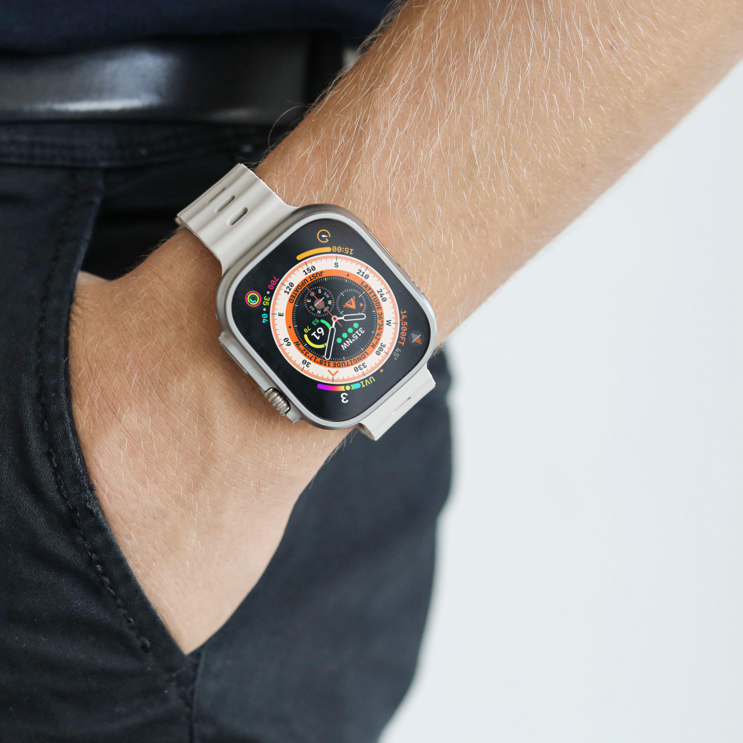 Das Handgelenk einer Person mit einer Smartwatch. Die Uhr ist silberfarben mit einem schwarzen und goldenen Bildschirm.