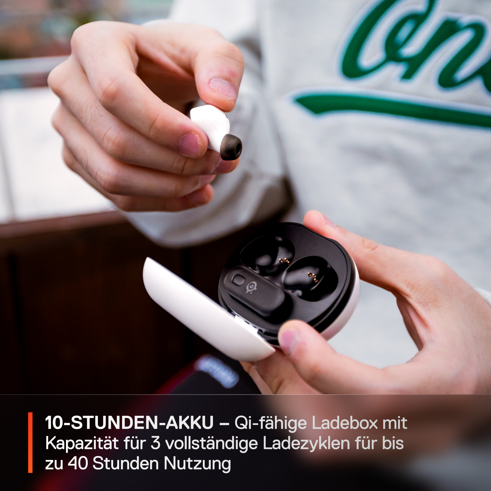 Hände, die ein weißes Ladecase mit Ohrhörern halten. Das Case ist geöffnet, die Ohrhörer sind sichtbar.