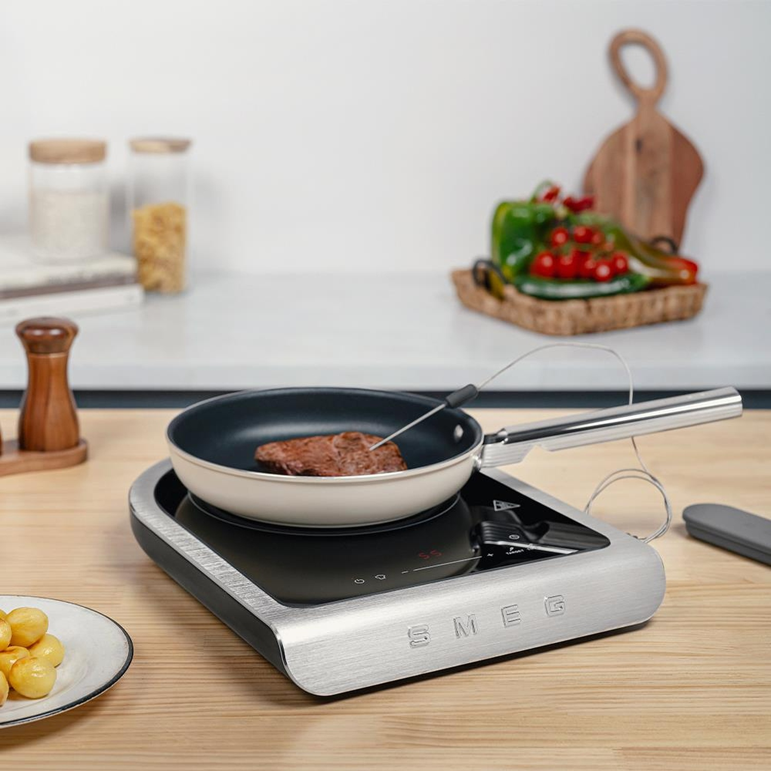 Una padella con bistecca che cuoce su un piano cottura a induzione SMEG.